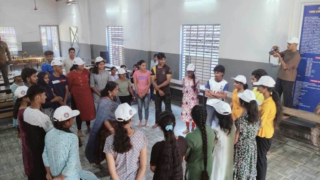 A group of young people wearing white caps gathered in an indoor space, engaging in a discussion or activity, with some individuals standing and others seated.