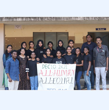 Group of students posing in front of a building holding a poster that reads 'DEC 10 2K21 ALL HUMAN, ALL EQUAL'.